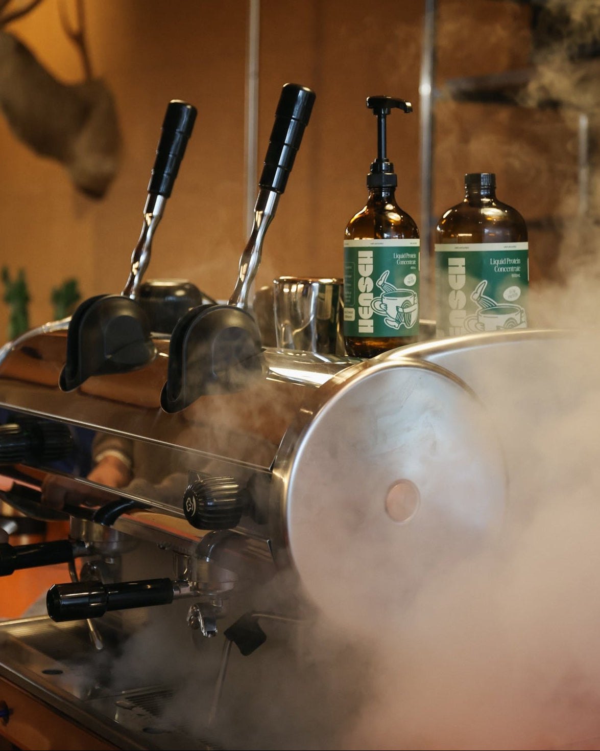 Steam rising from an espresso machine with Hensch bottles behind